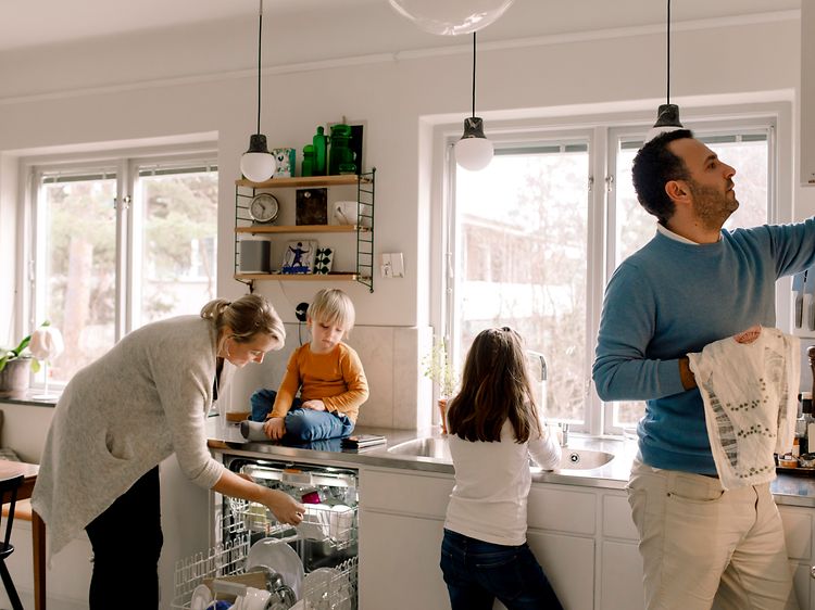 MDA-Dishwashers- Familie i et køkken, der tager et rent fad frem