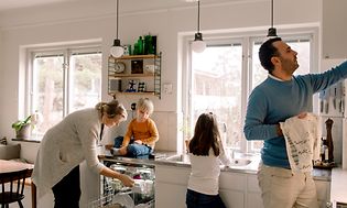 MDA-Dishwashers- Familie i et køkken, der tager et rent fad frem