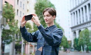 Sony Xperia-telefon i hånden på ung mand i byen