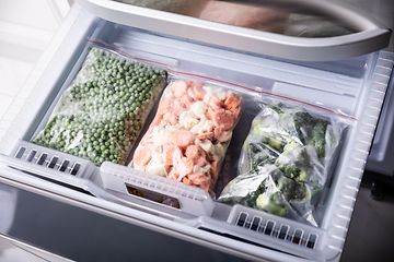 Tre plastikposer med frosne grøntsager i en fryser