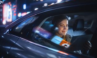 Ung forretningskvinde bruger en tablet på bagsædet af en taxi
