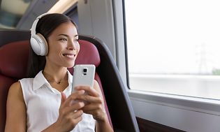 Forretningskvinde på tog med et noise cancelling headset