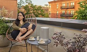 Kvinde sidder på en tagterrasse med Sonos Move på et cafébord