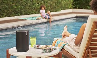 Sonos Move ved en pool på et bord ved siden af en kvinde