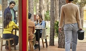 Kvinde bærer en Sonos Move udendørs forbi en cafe
