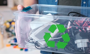 Bæredygtighed - Genbrug - En mand, der holder en kasse med gammel elektronik og et genbrugslogo