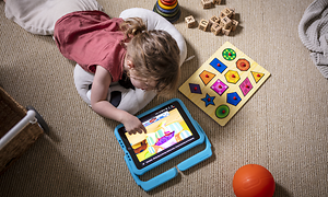 To børn, der ligger på gulvet og leger med en iPad med Orlando-cover