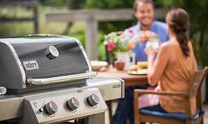 Gas grill og et par som spiser middag i baggrunden