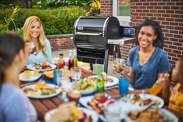 Hyggelig middag med en Weber træpillegrill i baggrunden