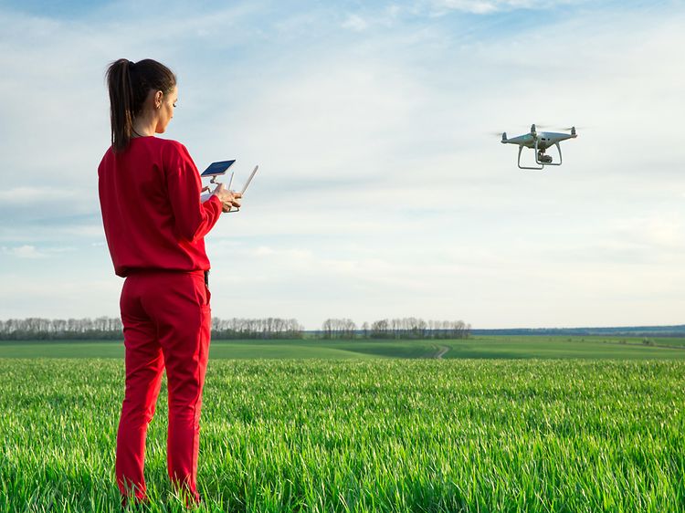 Kvinde flyver drone over en mark