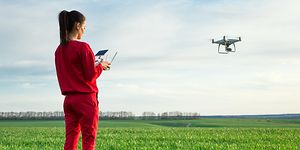 Kvinde flyver drone over en mark