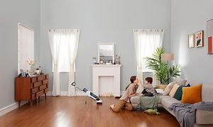 Roborock Dyad ledningsfri støvsuger i et rum, og en mor som leger med sit barn på sofaen