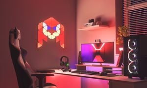 Skrivebord med gaming-setup og Nanoleaf smartbelysning på væg