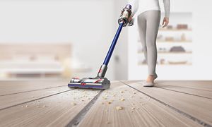 Kvinde rengør gulv med ledningsfri Dyson-støvsuger