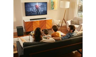 Familie i sofa ser TV udstyret med soundbar