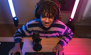Gamer foran skærm med belysning bag sig og mikrofon foran