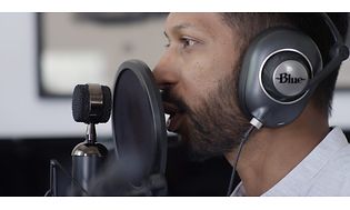En mand med hovedtelefoner foran en mikrofon med et popfilter