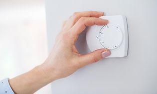 Nærbillede af kvindehånd som justerer termostaten
