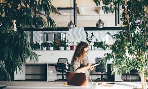 En kvinde på et kontor fyldt med grønne planter