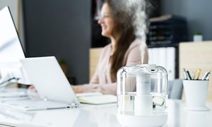 Luftfugter på et kontor med en kvinde i baggrunden som arbejder