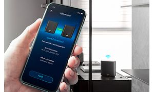 En hånd holder en en smartphone, som bruges til systemopsætning af mesh-netværk