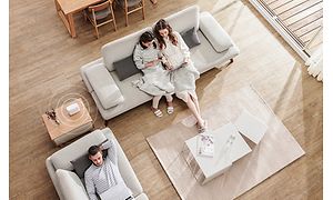 En familie i en stue hvor ZenWiFi mesh-systemet er diskret placeret på et lille bord