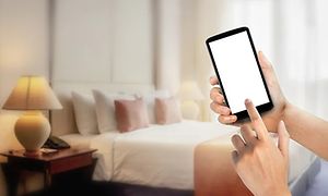 Hånd bruger smartphone i et soveværelse