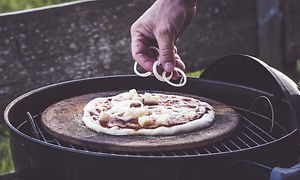 Hånd der putter fyld på pizza