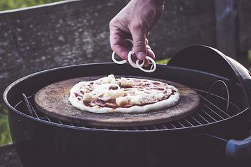 Hånd der putter fyld på pizza