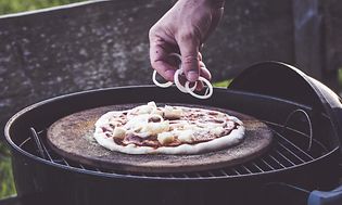 Hånd der putter fyld på pizza