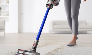 Kvinden rengør tæppe med Dyson V11 støvsuger