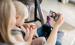 En kvinde og hendes datter taler med faderen under et videoopkald