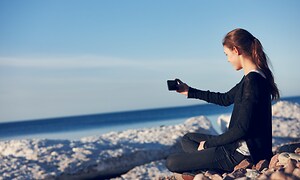 En kvinde ser på sin smartphone på stranden