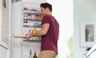 Mand tager madvarer ud fra et stort køleskab