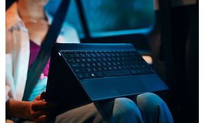 Kvinde sidder i en bil med en 2-i-1 pc i telttilstand