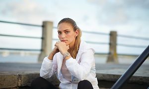 Garmin Vivomove på armen af kvinde, der sidder på trappe ved vandet
