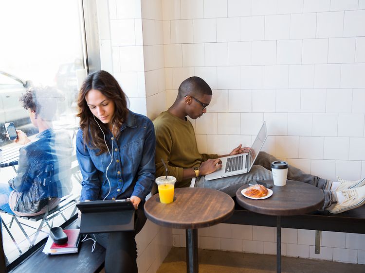 To personer sidder på en cafe og arbejder på deres bærbare computere