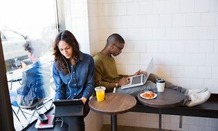 To personer sidder på en cafe og arbejder på deres bærbare computere