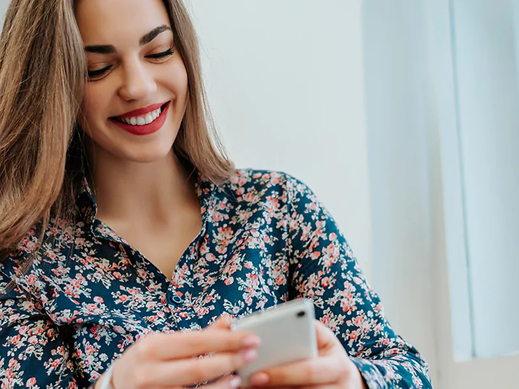 Smilende kvinde kigger på smartphone