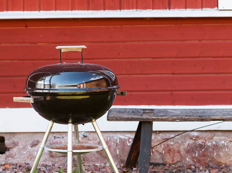 En grill foran et rødt hus