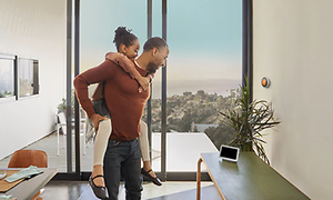 En mand, der bærer en pige, mens han ser på Google Nest Hub-skærmen