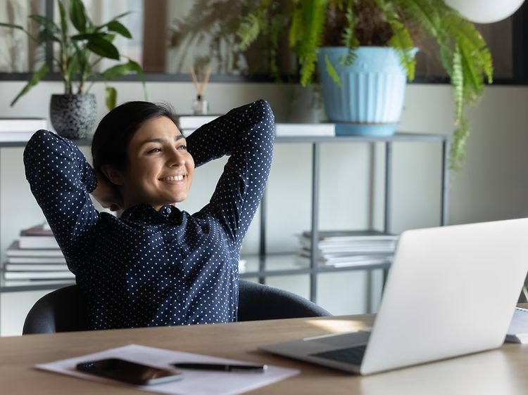 A woman leans back and looks happy and relaxed in her office