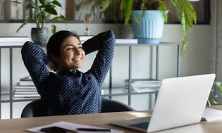 A woman leans back and looks happy and relaxed in her office