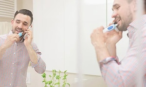  Elektrisk tandbørste - en mand, der børster tænder i et badeværelseman  brushing his teeth in a bathroom