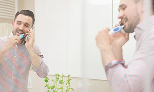 Elektrisk tandbørste - en mand, der børster tænder i et badeværelseman brushing his teeth in a bathroom