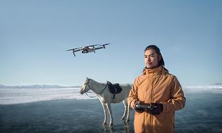 Drone flyves af mand, som står på tilfrosset sø