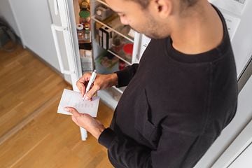 MDA-Køleskabe-Mand tager notater foran et åbent køleskab