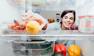 Kvinde rækker ud efter citron, som ligger i et køleskab