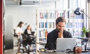 Mand smiler foran en computer på kontoret