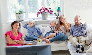 Familie i sofa foran TV